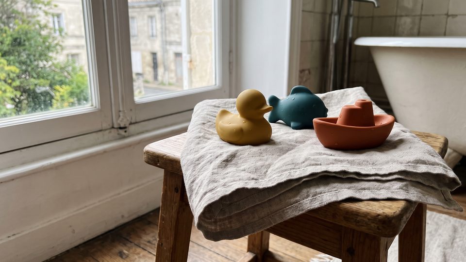 Jouets de bain en caoutchouc uni posés à sécher sur une serviette de lin pliée